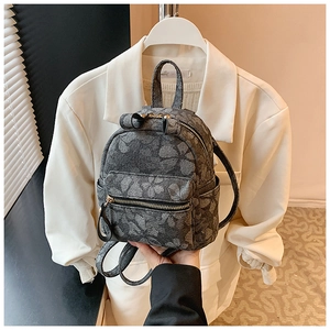 Detail of floral jacquard mini backpack with double zippers and side pockets held by model