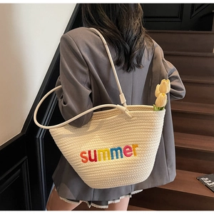Detail of woven straw tote bag with rainbow Summer embroidery and slim shoulder strap