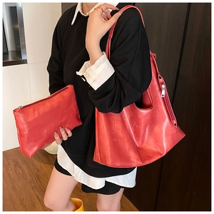 Detail of red leather tote bag with matching zippered pouch showing texture and size