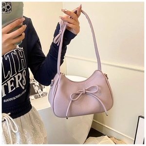 Detail of lavender dumpling bag with lychee texture and bow accent on long shoulder strap