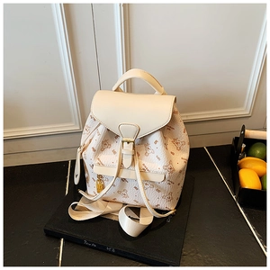 Close-up of bear and letter printed pattern with golden metal buckle on cream faux leather backpack