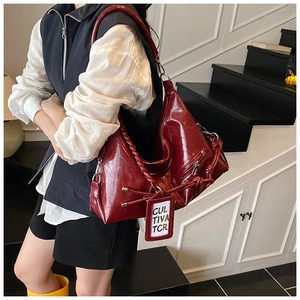 Deep red glossy leather tote bag featuring a woven handle and textured surface details