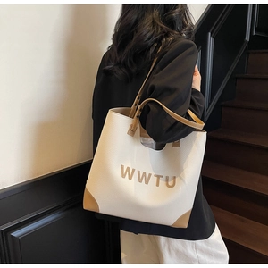 Model wearing a large ivory and brown contrast tote bag with WWTU lettering