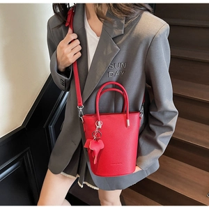 Detail of red bucket bag featuring lychee grain texture and a cute elephant charm