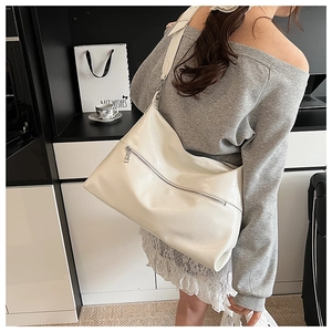 Macro detail of glossy white shoulder bag featuring a front metal zipper and wide strap