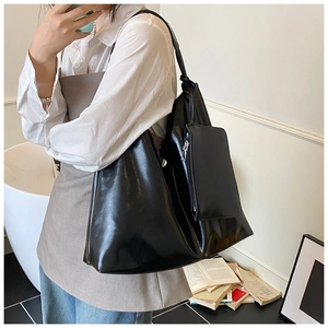 Macro detail of black glossy tote bag with minimalist knotted straps and detachable pouch