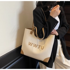 Detail of the large beige tote bag with brown handles and 3D WWTU lettering