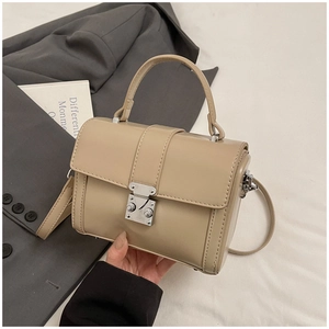 Detail of a beige PU leather handbag with silver vintage buckle on a dark suit background