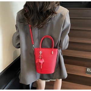 Detail of red bucket bag with lychee texture leather and a cute elephant charm accessory