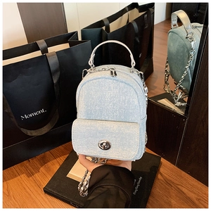 Detail view of mini denim backpack with silver chain strap and metal swivel lock closure