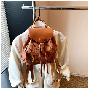 Detail of brown faux leather backpack with bear print and cute smiley face charm