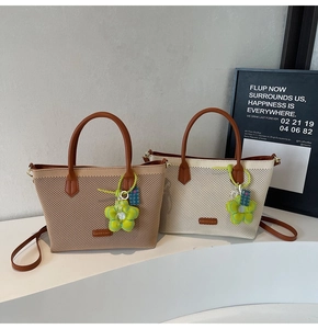 Détail d'un sac cabas tissé avec poignées en cuir et breloque fleur verte