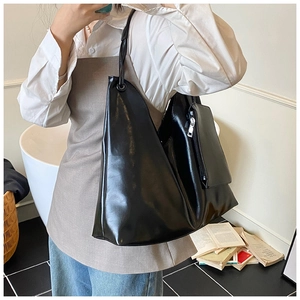 Detail view of a black minimalist bucket tote bag with matching pouch and slim straps