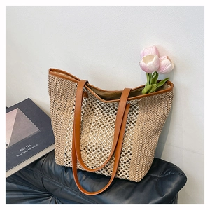 Detail of woven straw tote bag with cutout mesh design and brown leather straps