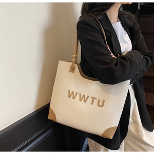Close-up of the large tote bag showing textured cream leather and brown accents