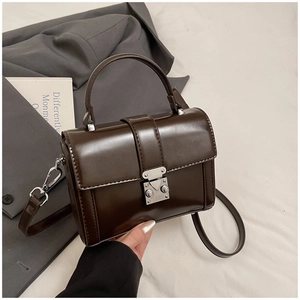 Detail of premium brown faux leather bag showing silver metal push lock and smooth finish