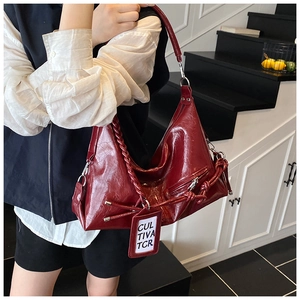 Detail of burgundy leather tote bag with woven strap and decorative tag for daily commute