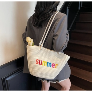 Detailed texture of cream woven tote bag with colorful summer embroidery on the front