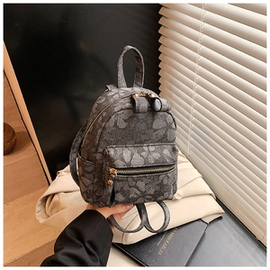 Detailed close-up of gray floral mini backpack with gold zippers and textured canvas material