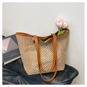 Detail of hollow diamond weave pattern on large straw tote bag with brown leather handles