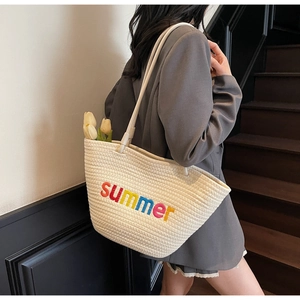 Detail of a cream woven tote bag with colorful summer embroidery on a model