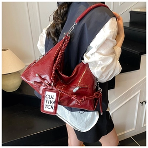 Close-up of wine red patent leather tote bag with woven handles and metal zipper detail