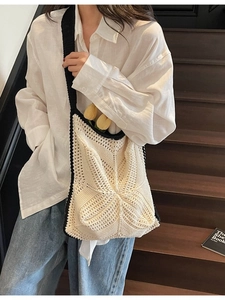Handmade crochet tote bag with contrast piping and star texture on wooden stairs