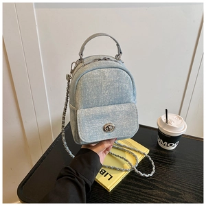 Detail of light blue denim mini backpack with silver metal turn-lock and chain strap