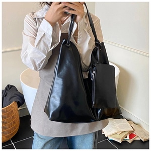 Detail view of large black patent leather tote bag with matching small pouch accessory