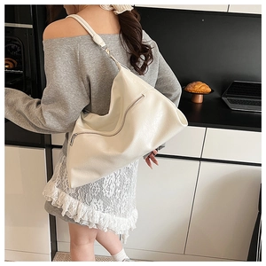 Detailed view of cream white large capacity shoulder bag worn in a modern kitchen setting