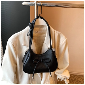 Detail of black litchi leather shoulder bag with decorative bows and silver hardware