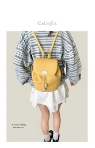 Detail of yellow lychee leather backpack with drawstring closure and white oval logo