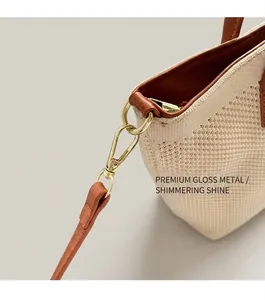 Gros plan sur le sac fourre-tout tissé beige avec crochet en métal doré et bordure en cuir