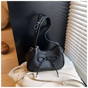 Detail of black lychee leather shoulder bag with decorative bows and silver hardware