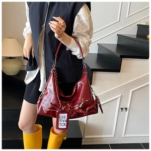 Detail of burgundy patent leather tote bag featuring woven strap and side zipper pocket
