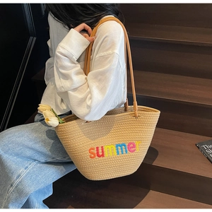 Detail of woven straw tote bag with colorful summer embroidery and leather straps