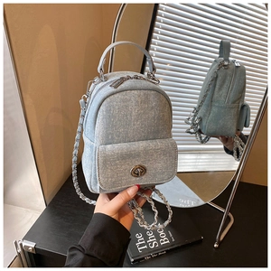 Detail of light blue washed denim mini backpack with silver chain strap and twist lock