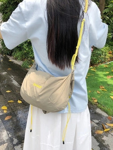 Outdoor shot of lightweight nylon khaki crossbody bag with yellow drawstring and embroidery