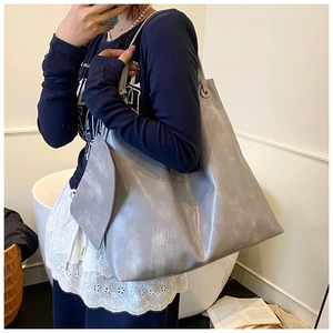 Large grey tote bag with washed texture shown on shoulder for size reference