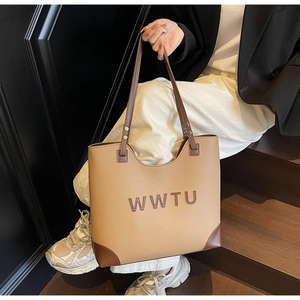 Detail view of large tote bag with WWTU lettering and reinforced corners on wooden stairs