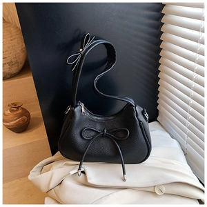 Detail of black litchi grain texture and elegant bow design on a stylish crescent bag