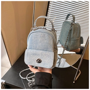 Detail of light blue denim mini backpack with metal twist lock and chain strap texture