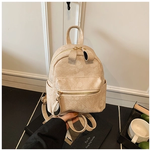 Detailed macro view of beige embossed leather texture and front zipper pocket on mini backpack