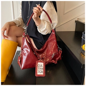 Detail of dark red vintage faux leather hobo bag with braided strap and silver metal zipper