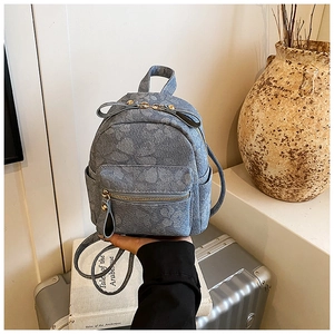 Close-up of blue floral denim mini backpack with golden zipper and metallic hardware