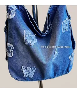 Close-up of blue denim tote bag with distressed letter patches and frayed edges