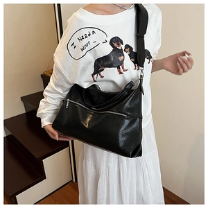 Close-up of black PU leather tote bag with silver zippers and wide shoulder strap