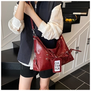 Detail view of burgundy leather tote bag with thick woven strap and white cultiva tag