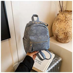 Detailed close-up of light blue denim mini backpack with 3D floral jacquard pattern