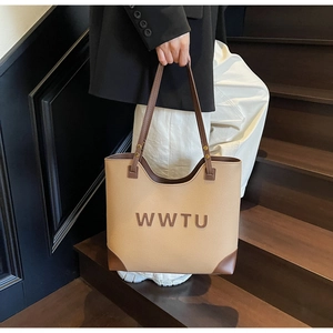 Close-up of WWTU letter print on vintage beige leather tote bag with dark brown straps